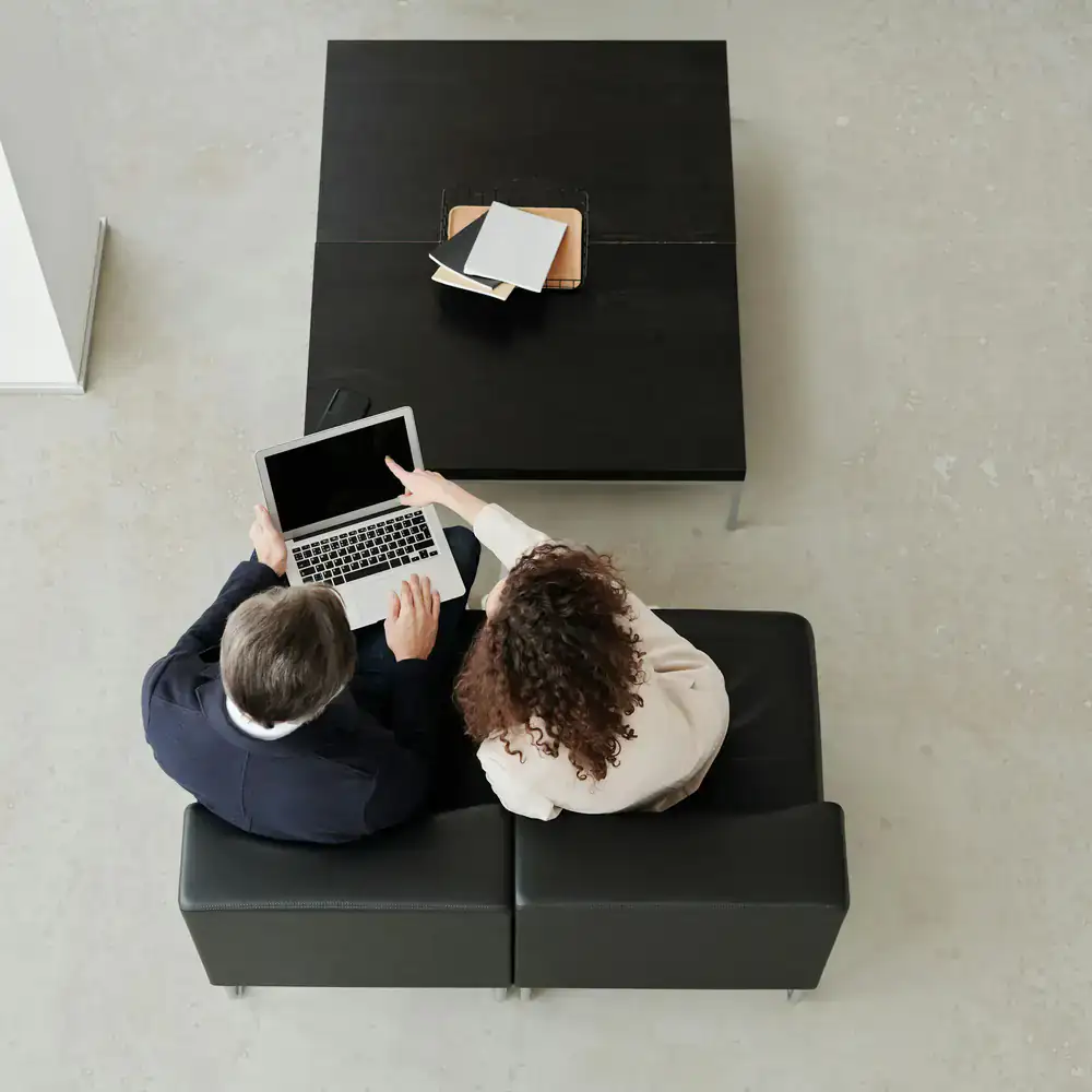 Two colleagues discussing a project while looking at a laptop